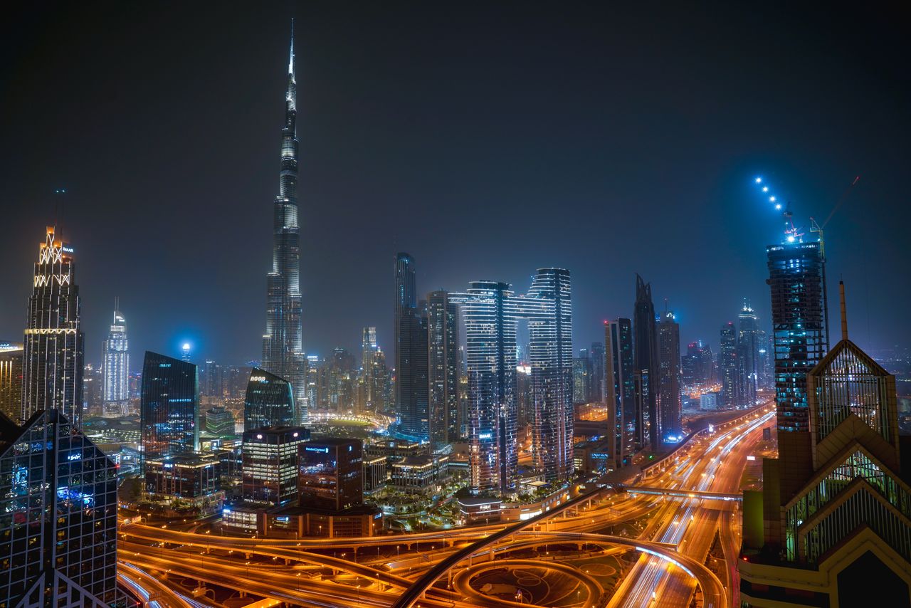 Beautiful night view of Dubai city skyline with Burj Khalifa towering over illuminated roads and skyscrapers.